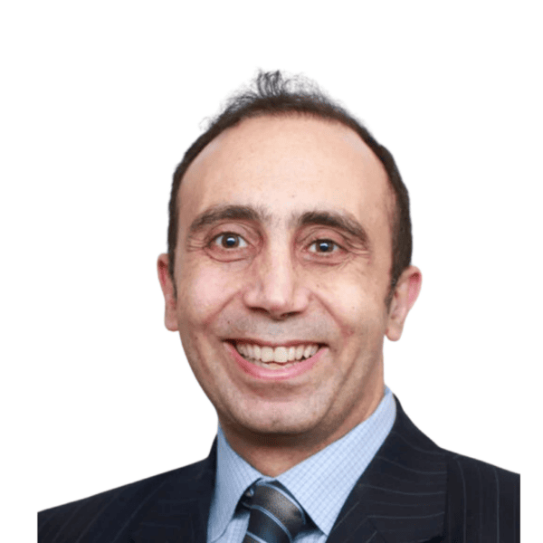 Smiling man in a dark pinstripe suit, blue shirt, and striped tie, with short dark hair, standing against a plain white background.